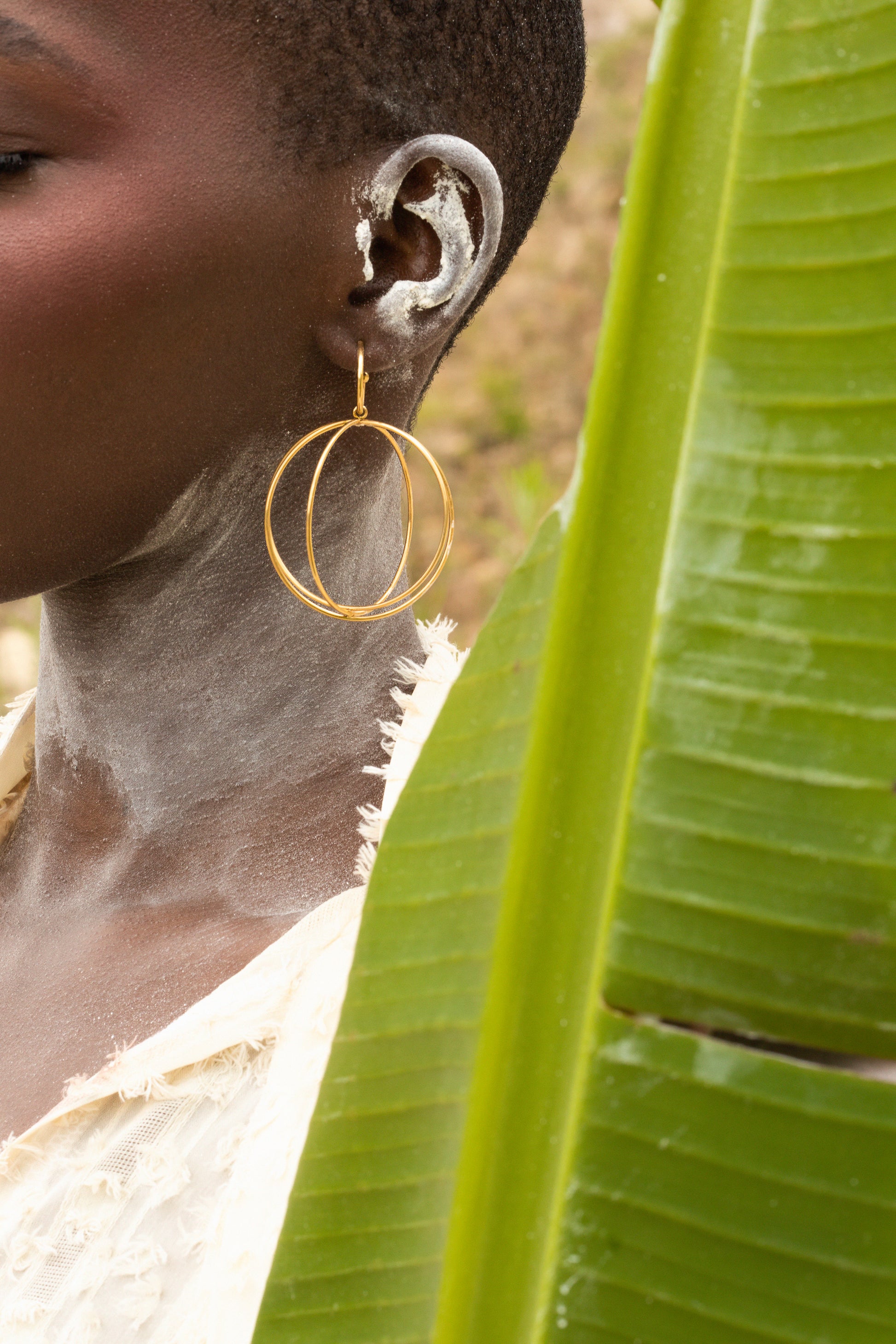 A black model wearing Zvet gold plated intertwined hoops symbolizing ubuntu philosophy