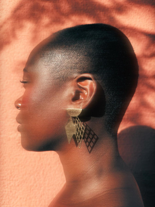 Efa earrings celebrates women's femininity. Black woman with short hair wearing Gold plated statement earrings for accessoires 